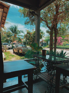 Two movers dismantling a wooden dining table outside a modern home under clear skies.