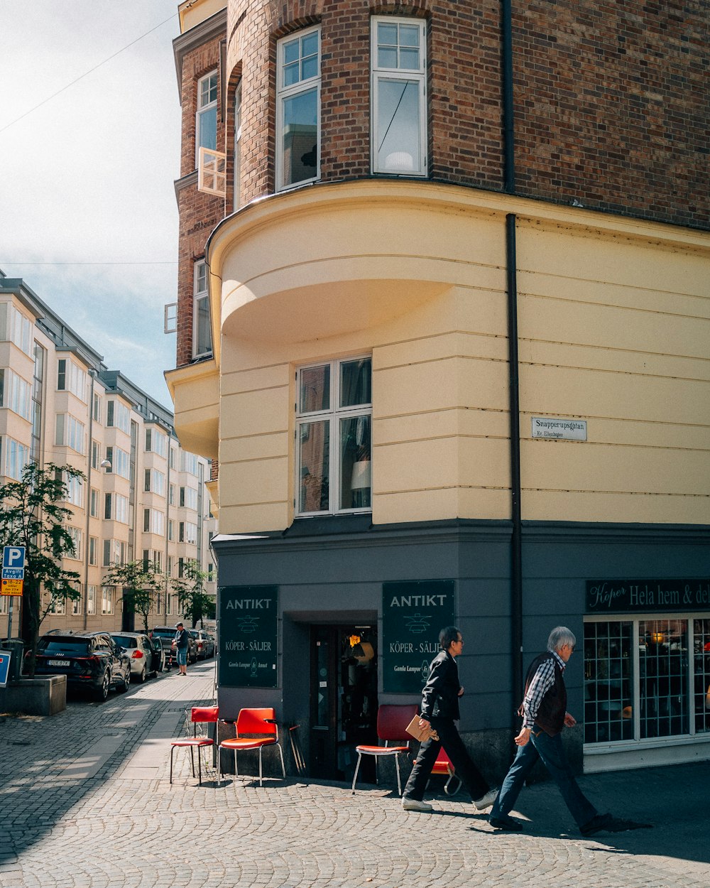 a couple of men walking down a sidewalk next to a building