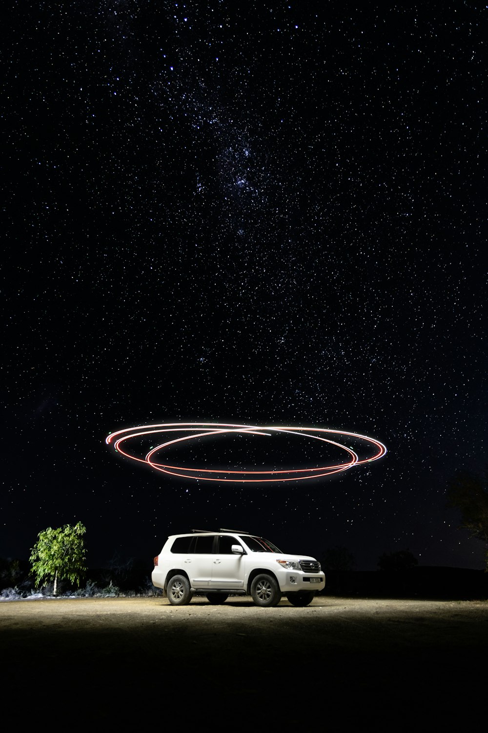 a car parked in front of a red circle in the sky