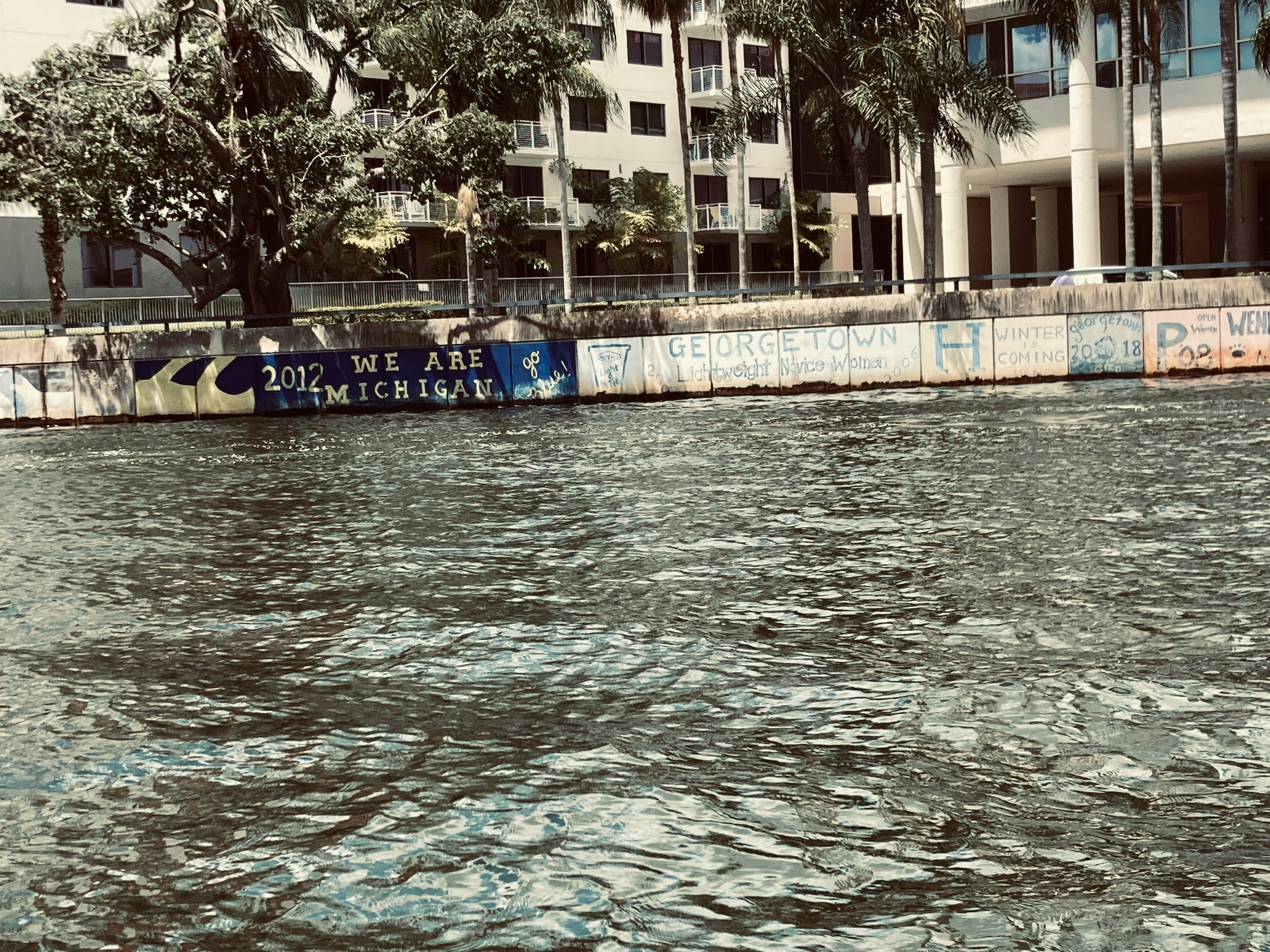 a body of water with a wall and buildings in the background