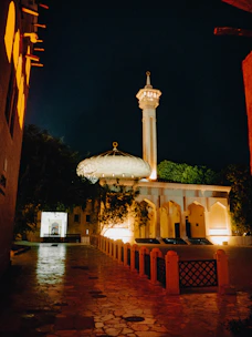 Sunlight softly illuminating the entrance of Baitun Noor Masjid with community members greeting each other.