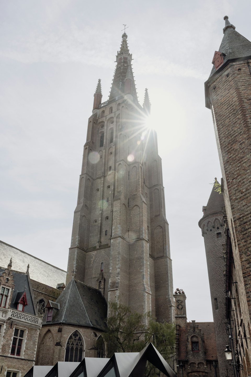 The brick spire of the Church of Our Lady rising above Bruges' rooftops