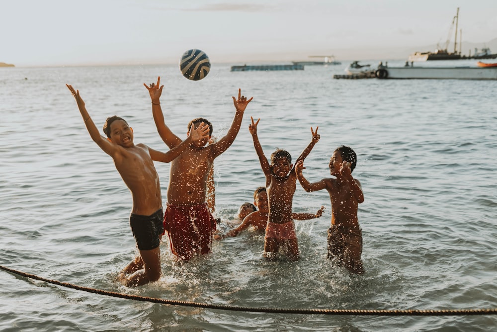 a group of people playing volleyball in the water