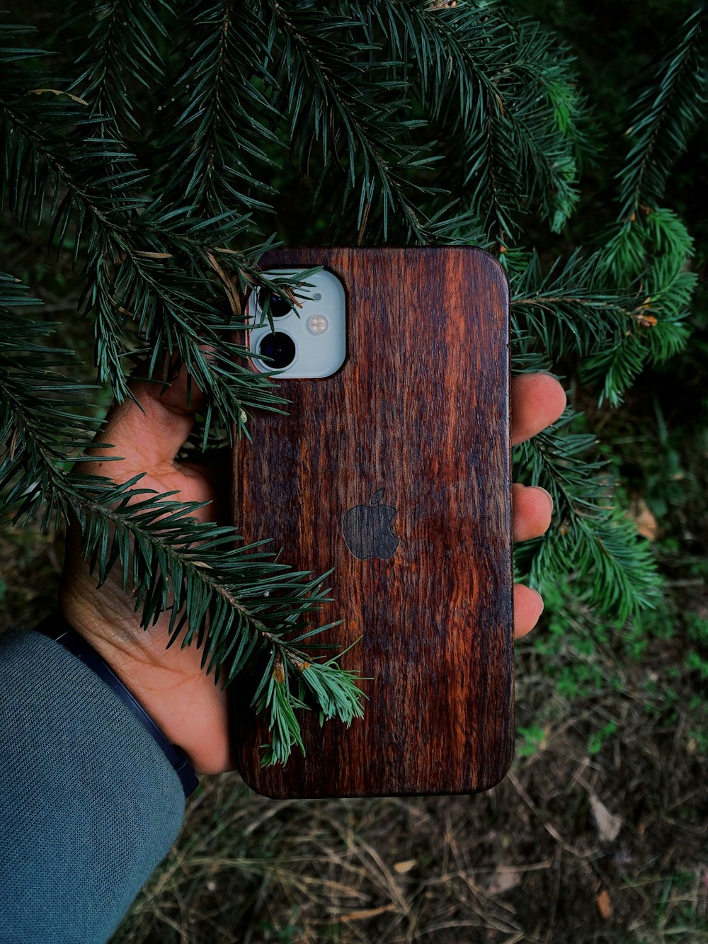 a hand holding a small wooden box with a camera on it