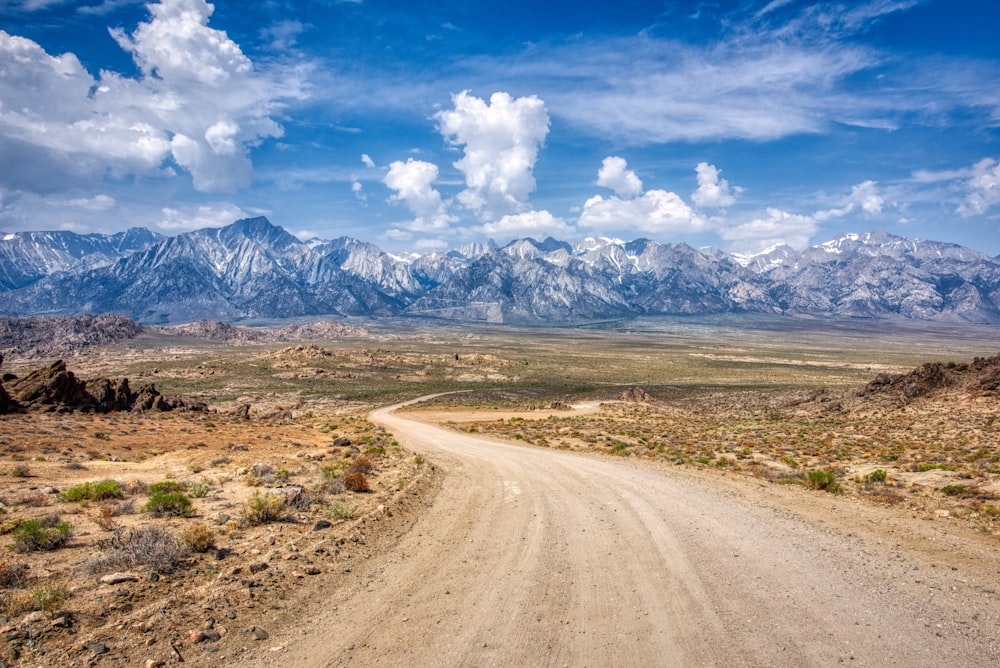 a dirt road leading to a mountain range
