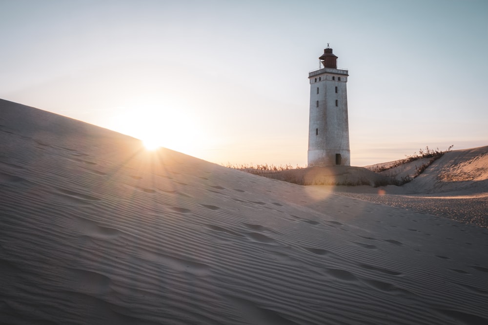 a light house sitting on top of a sandy hill