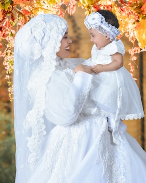 A warm, candid photo of Marcela holding her daughter Laura, surrounded by elegant clothing designs.