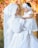 Smiling mother holding her baby dressed in a white baptism gown outdoors