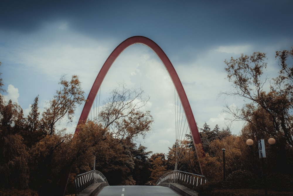 a roller coaster with trees and a blue sky with Gateway Arch in the background