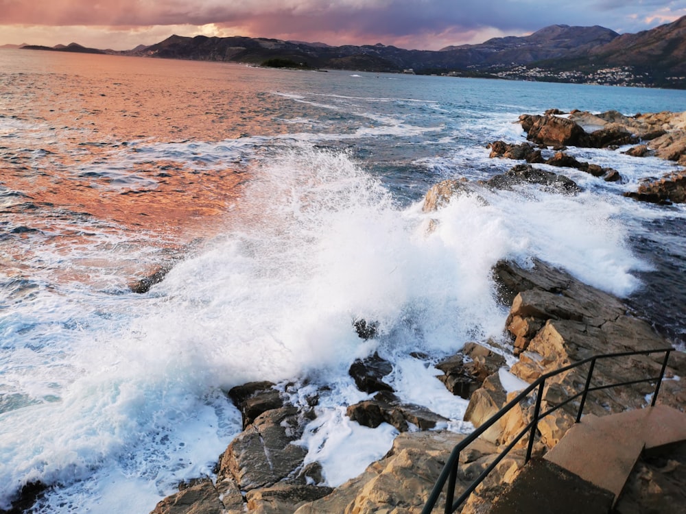 a rocky beach with a body of water in the background