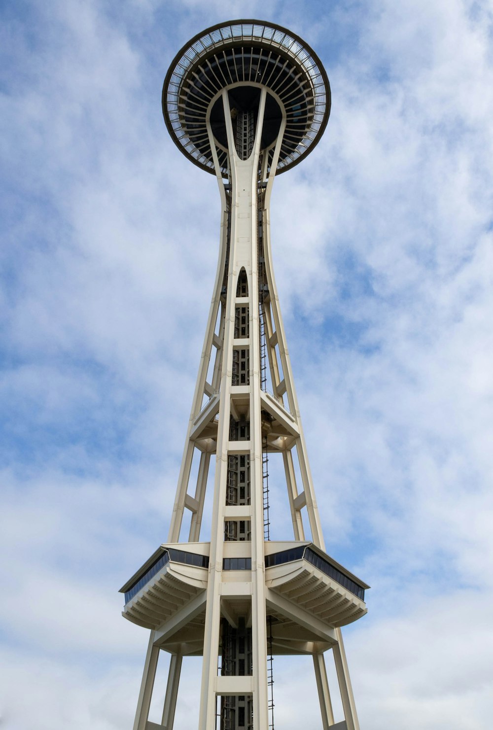 a tall tower with a circular top with Space Needle in the background