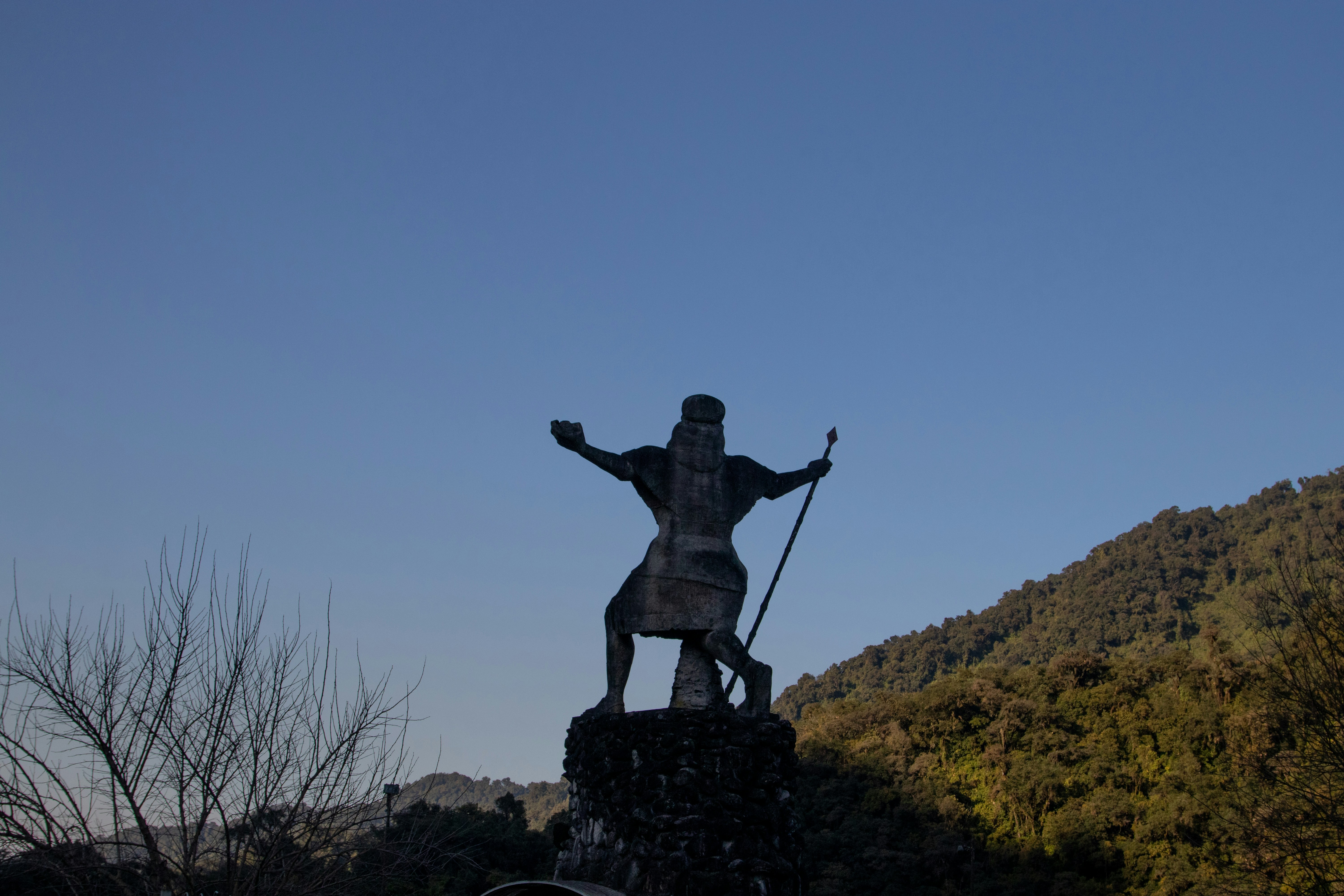 a statue of a man with a spear on top of a hill