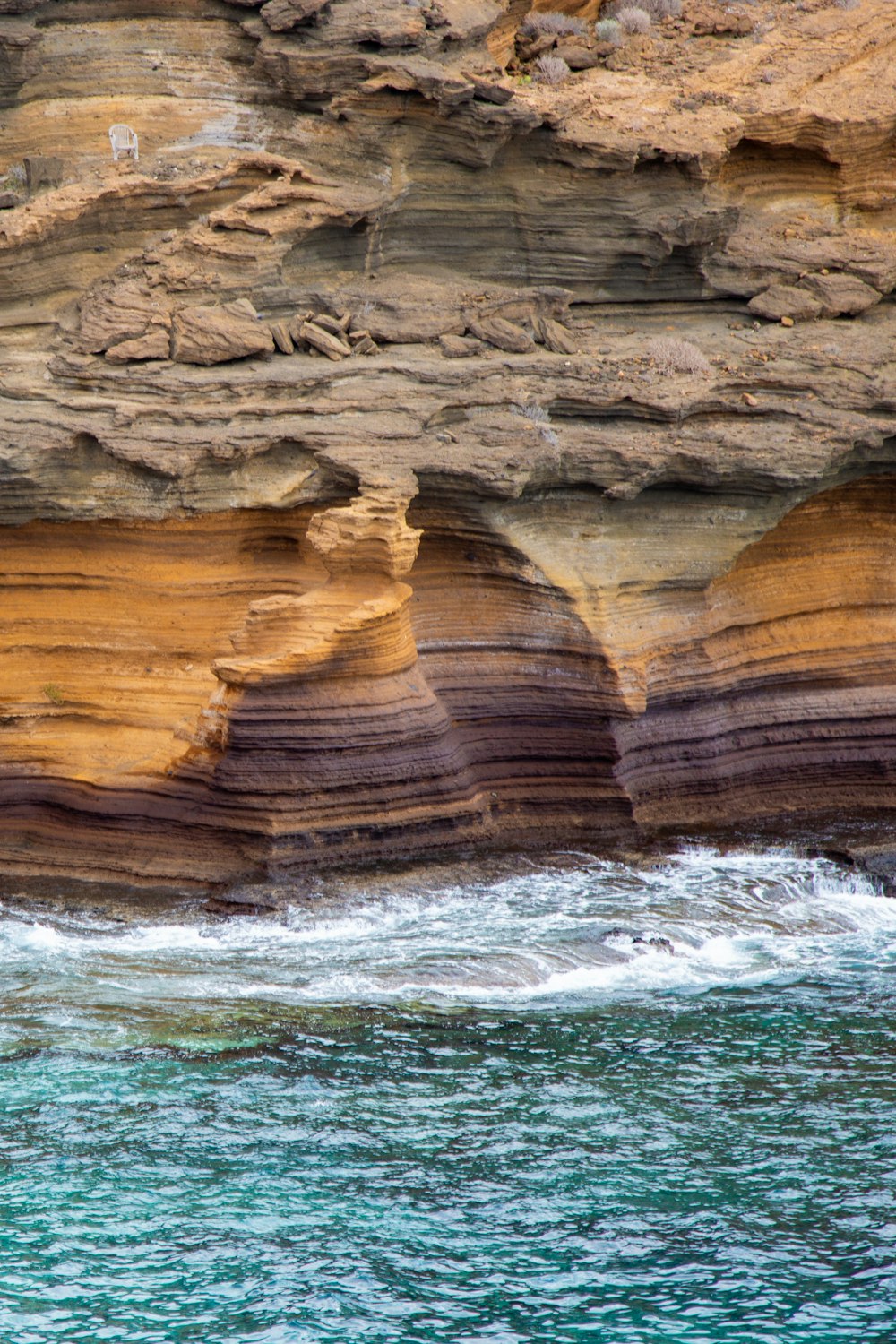 a rocky cliff with a body of water below