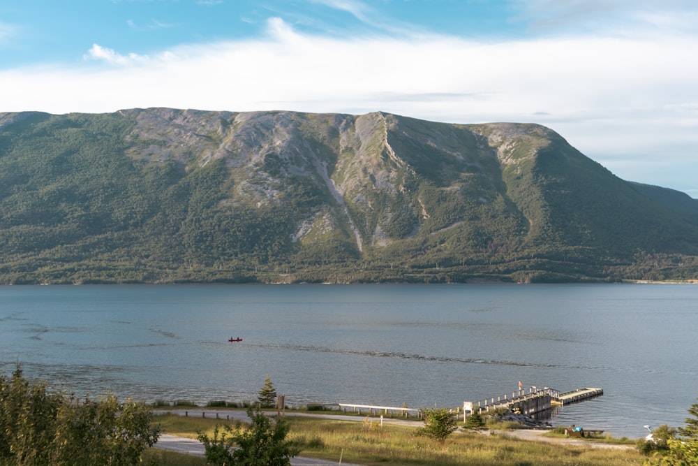 a body of water with a dock and a mountain in the background