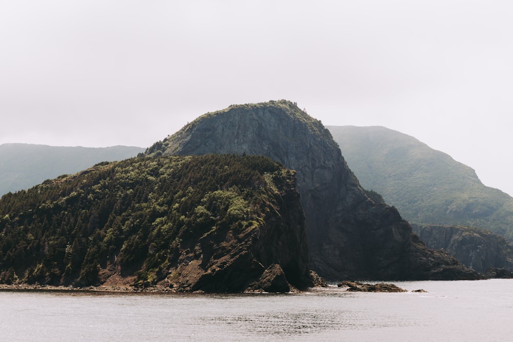 a rocky mountain with a body of water in front of it