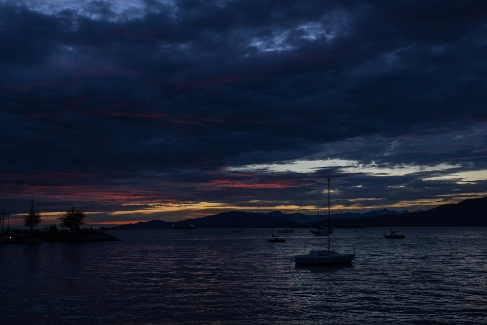 a group of boats in a body of water with a sunset in the background