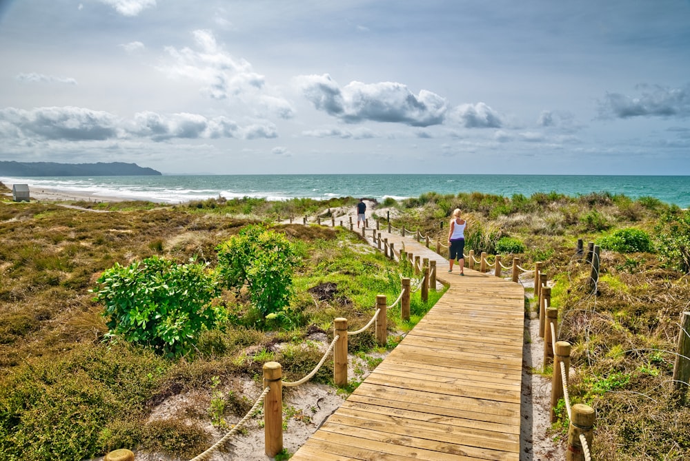 a person walking on a wooden bridge over a beach