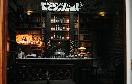 A cozy vintage library corner with a classic speakeasy vibe, featuring old books, cocktail glasses, and warm amber lighting.