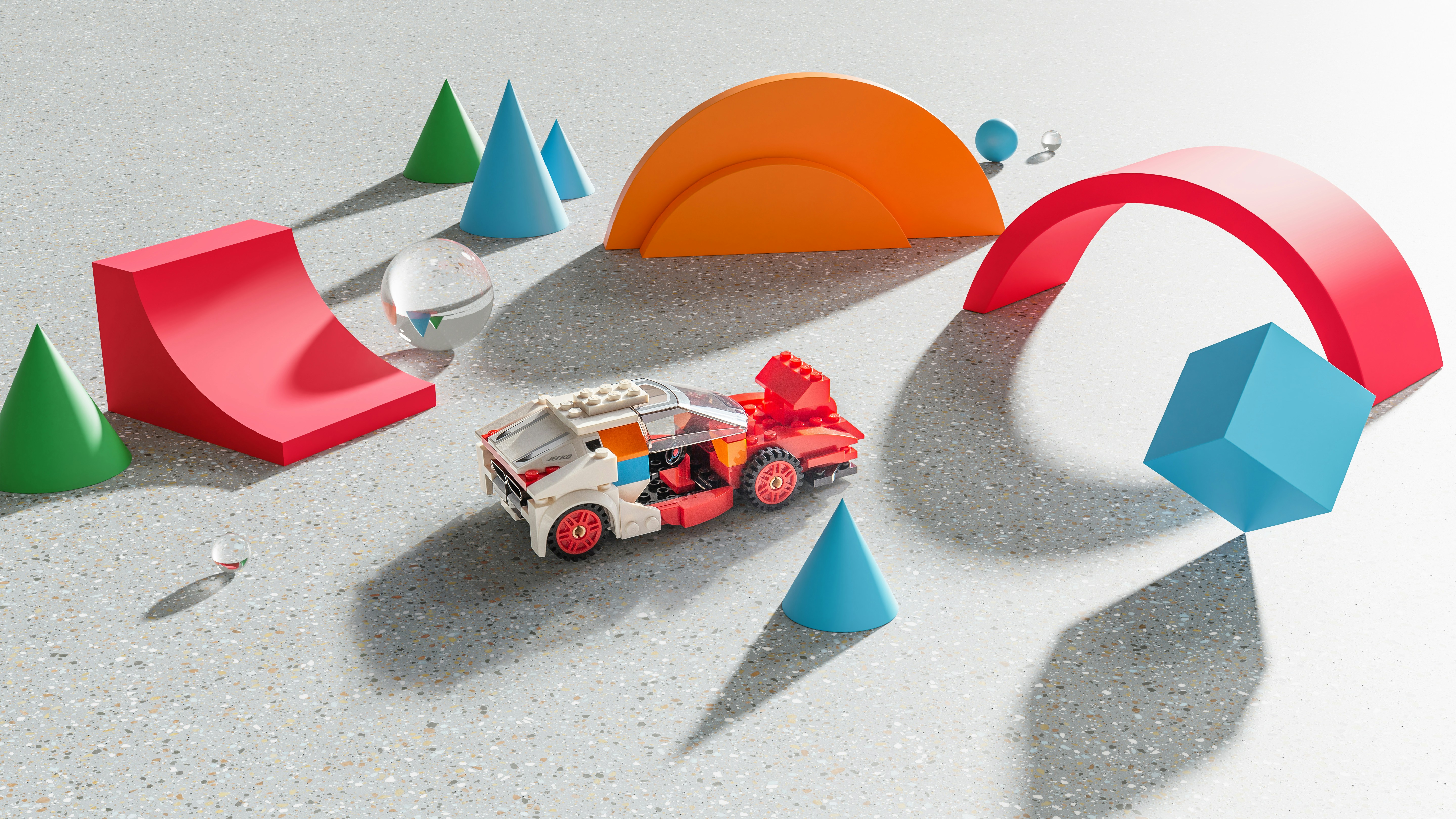 Lego car driving through an imaginary world of bright colourful shapes. Car is made from lego, the scene is made in Blender.