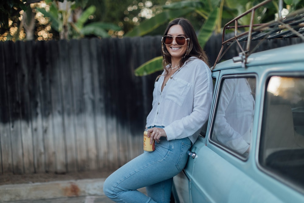 a woman leaning on the side of a blue van