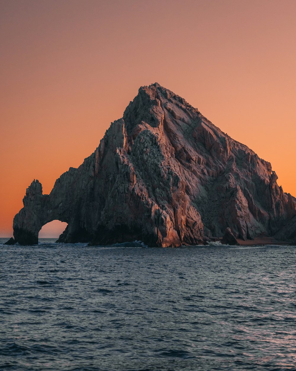 a body of water with a rocky cliff in the background