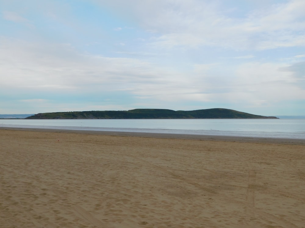 a sandy beach with a hill in the distance