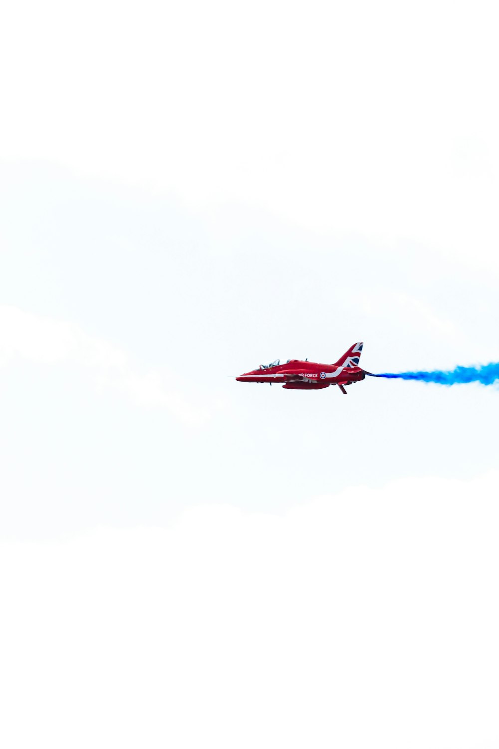 a red plane with blue smoke
