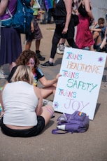 a couple of women sitting on the ground holding a sign