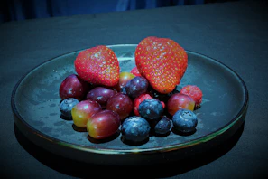 Elegant display of assorted frozen fruits arranged on a dark slate surface with gold accents