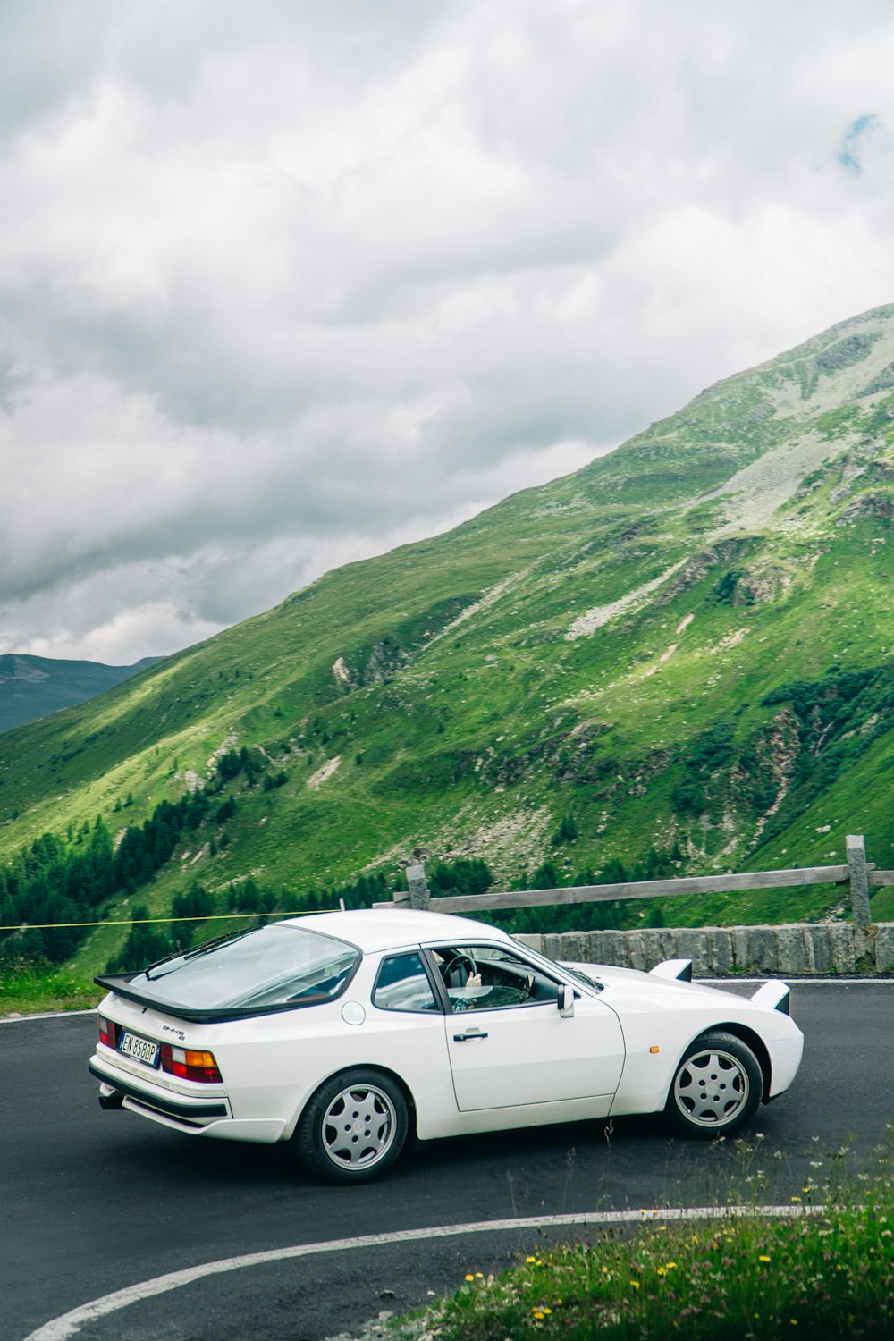 a white car parked on a road with a mountain in the background