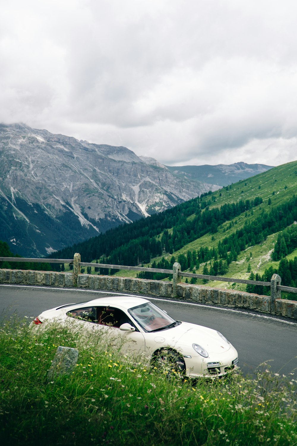 a white car on a road with mountains in the background