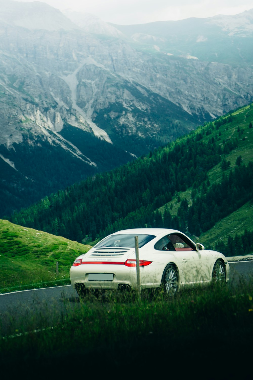 a white car driving on a road with mountains in the background