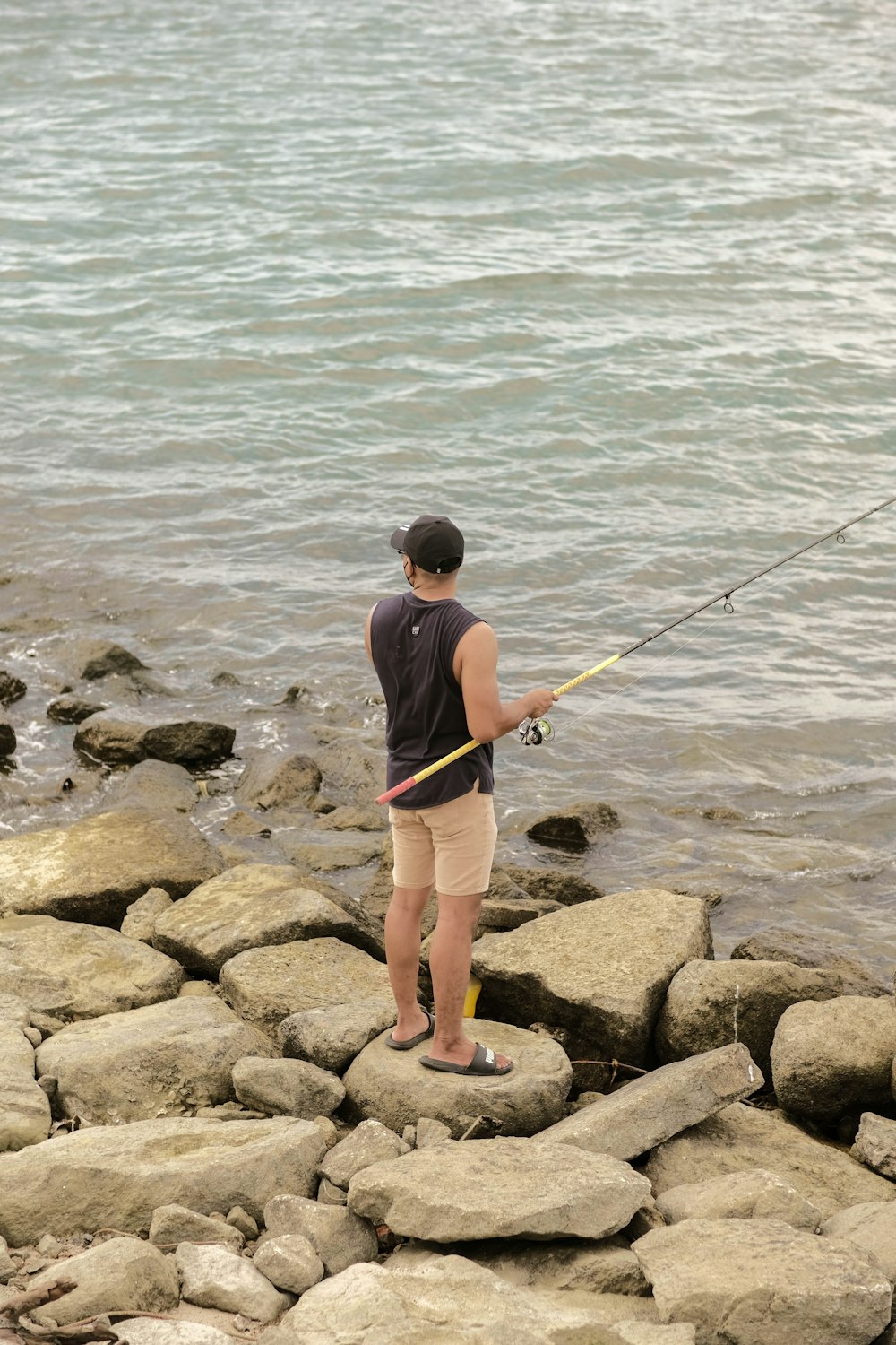 a person fishing on a rocky shore