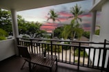 Bright room with a balcony overlooking a tropical beach at sunset.