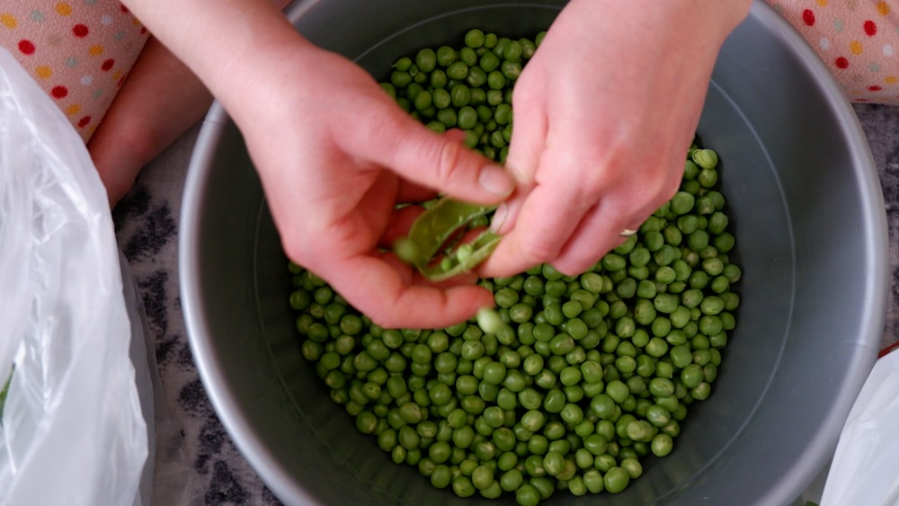 a person holding a bowl of peas