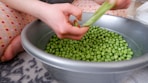a person holding a bowl of peas