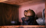 A collection of stoneware pots displayed on a minimalist wooden shelf.