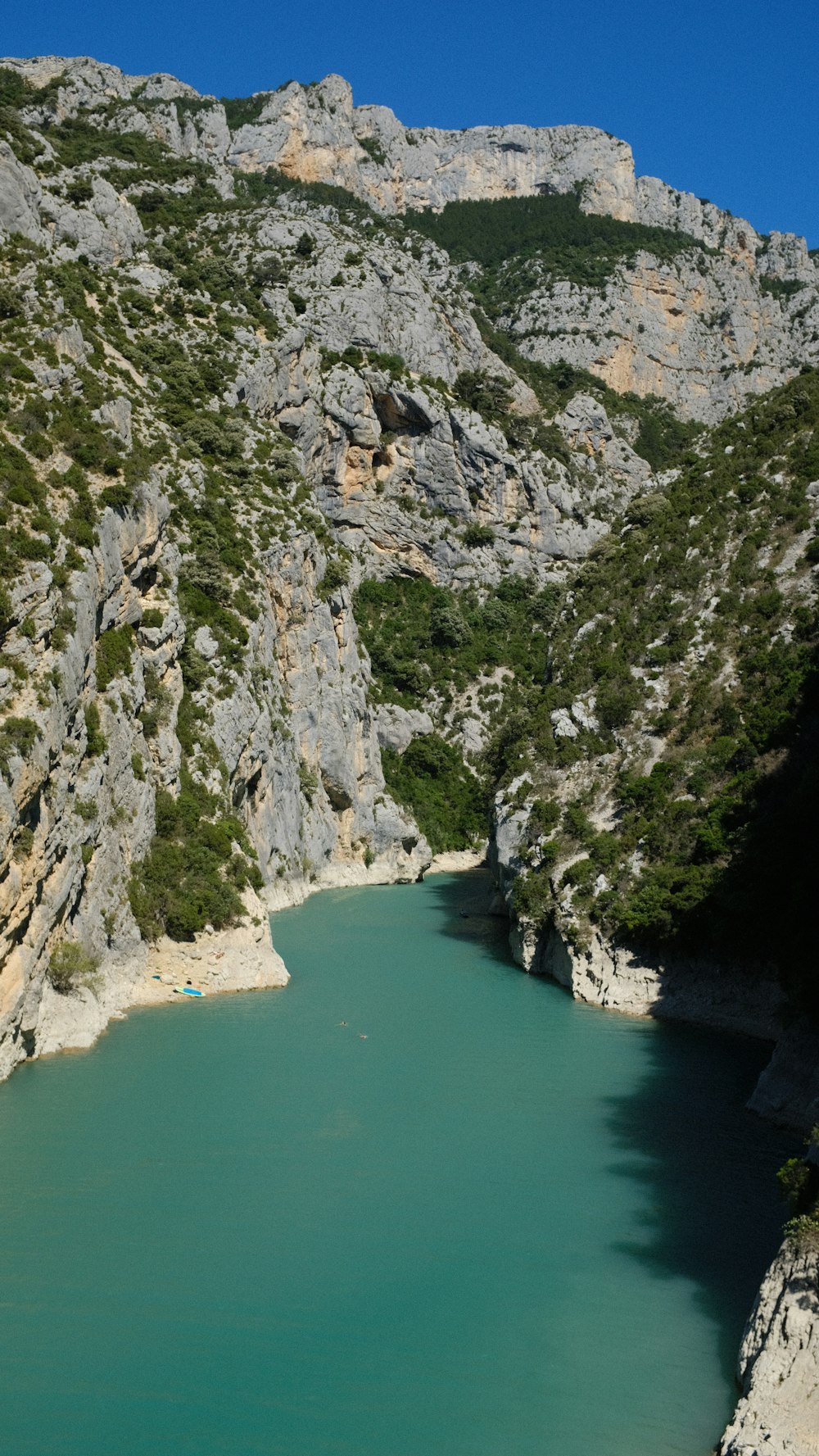 un acantilado rocoso con un cuerpo de agua debajo con Verdon Gorge al fondo