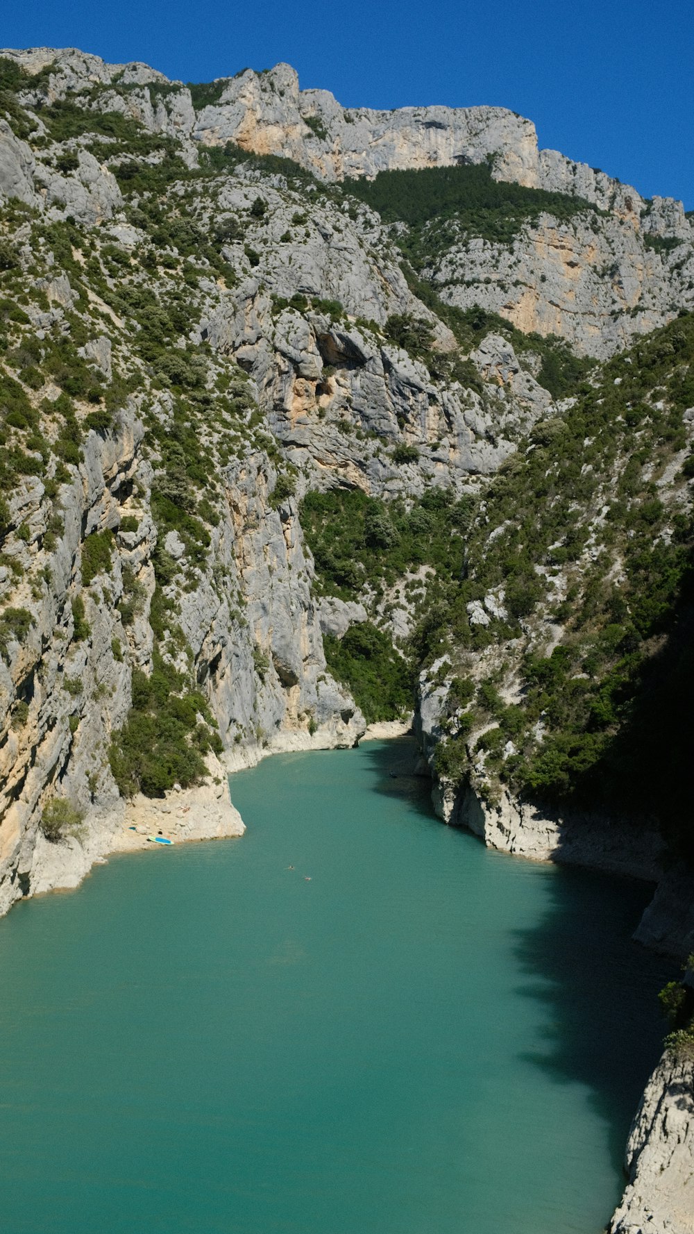 a rocky cliff with a body of water below with Verdon Gorge in the background