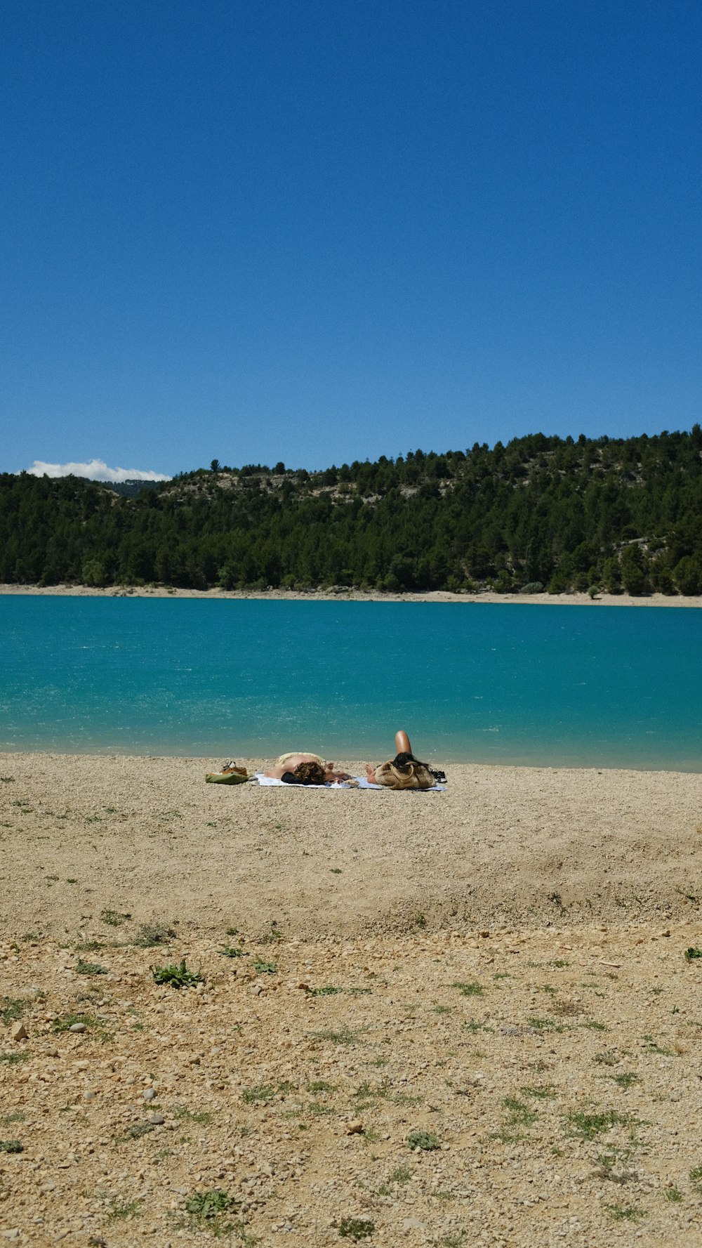 a couple of people lying on a beach by a body of water
