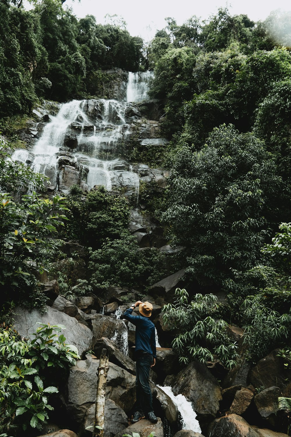 a person standing on a rock near a waterfall