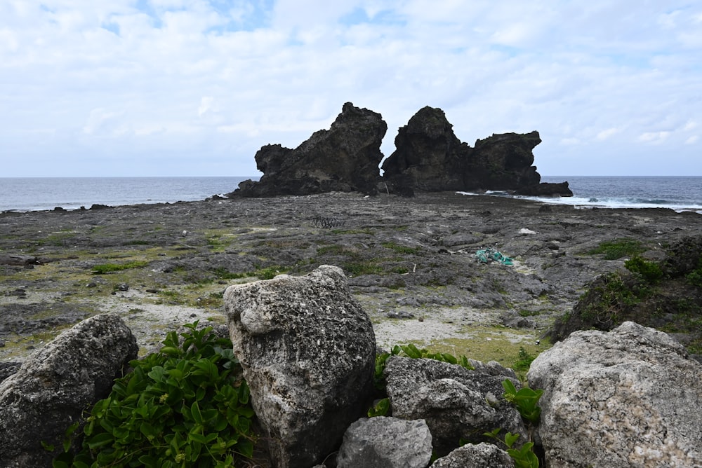 Ein felsiger Strand mit ein paar großen Felsen im Wasser