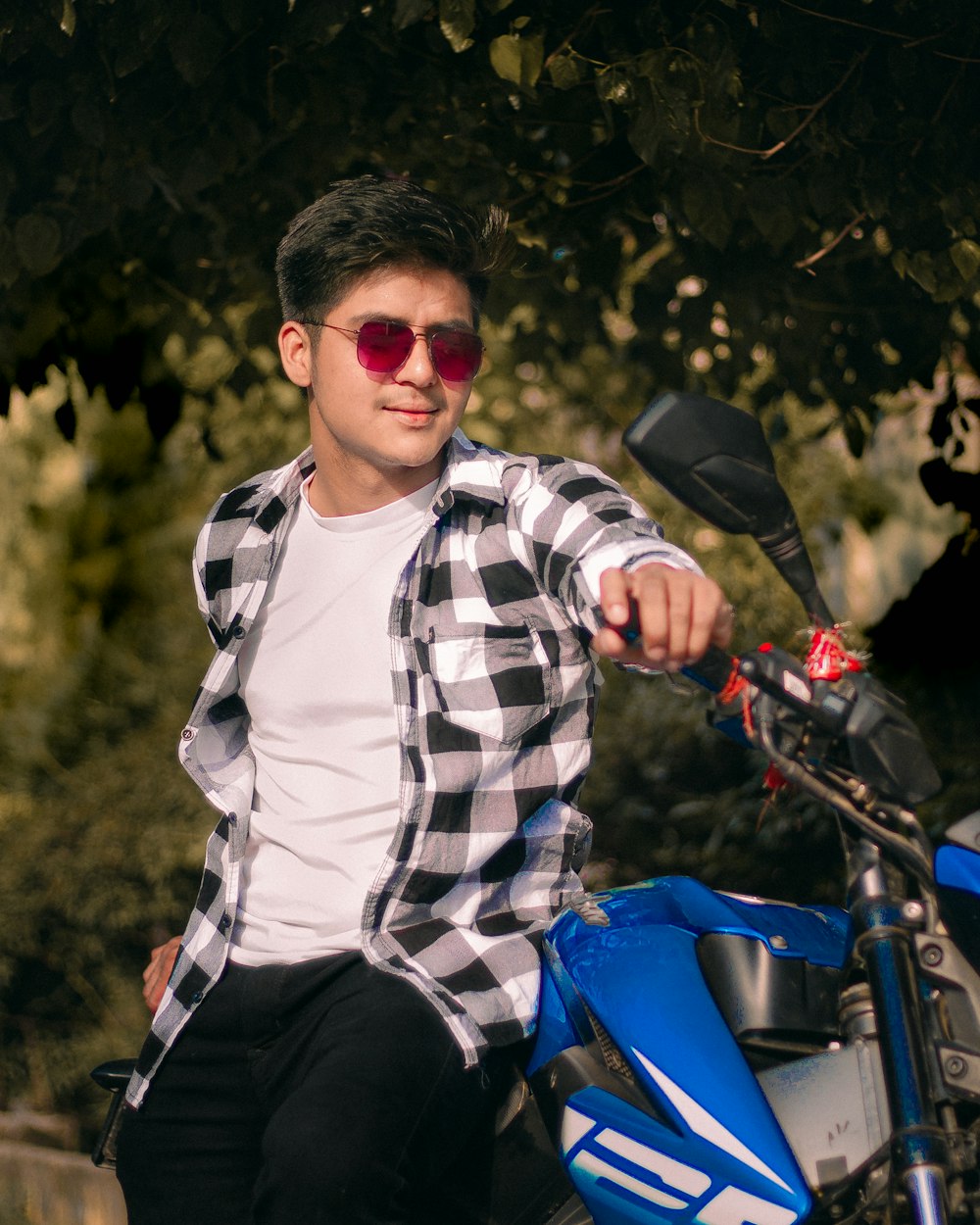 a person wearing sunglasses and standing next to a motorcycle
