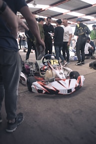 A team of kart racers and coaches discussing setup adjustments beside a kart.