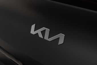 A sleek, metallic emblem with a modern design is displayed against a matte black background. The emblem appears to be the logo of a brand, possibly an automotive company.
