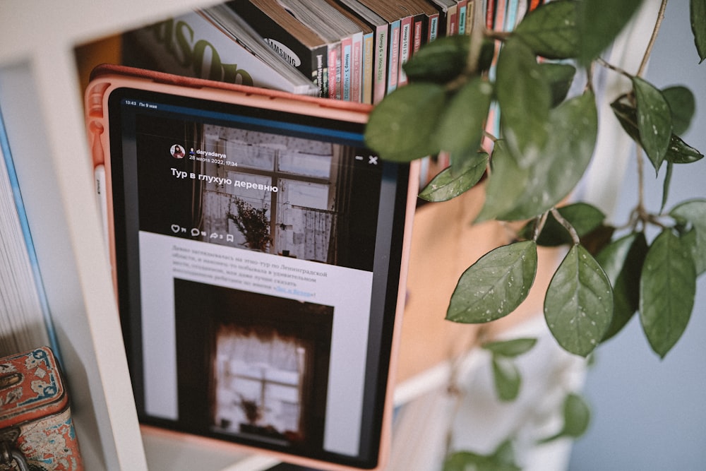 a black and white tablet on a table with a plant and books