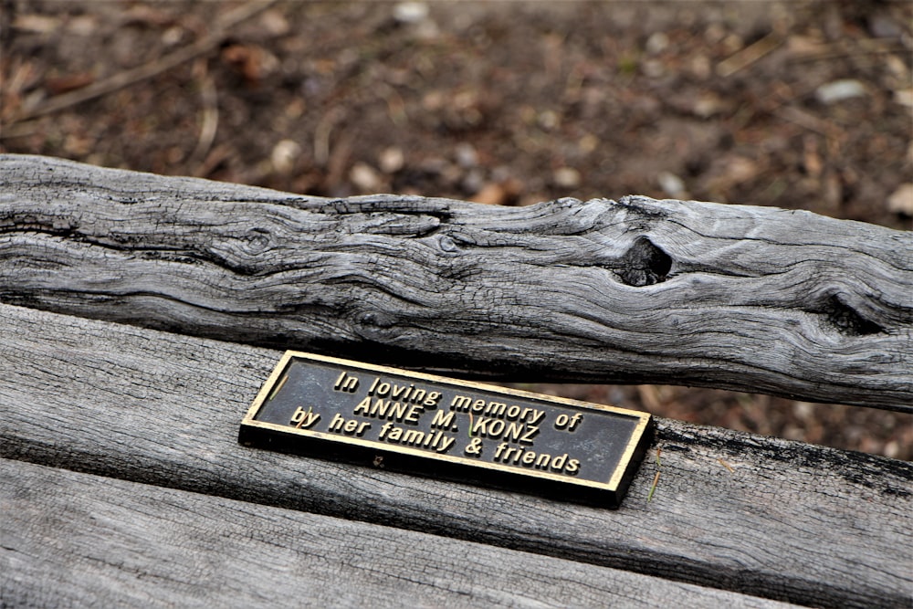 a black and gold engraved plaque on a log
