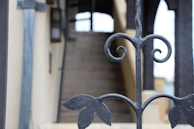 Ornamental aluminum fence with intricate scrollwork in a rich bronze finish framing a garden pathway.