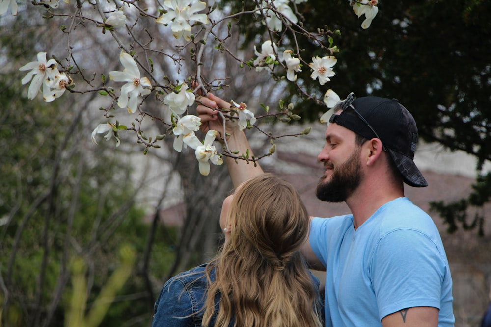 a man and woman looking at a tree with white flowers
