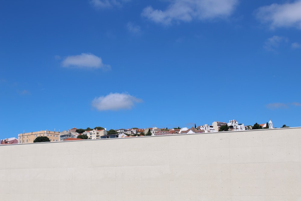 a white wall with a blue sky and clouds above it